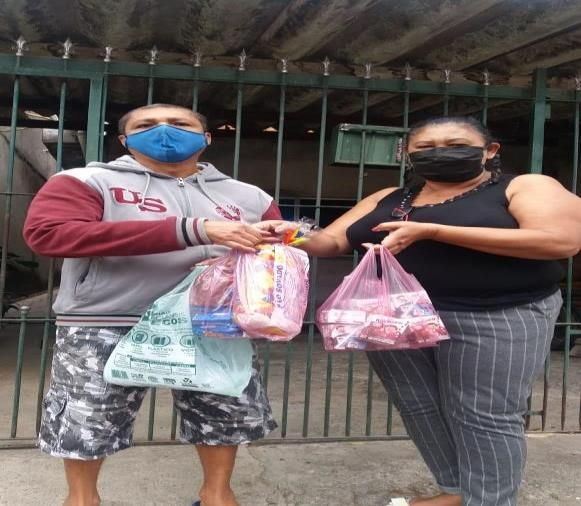Educadora entregando kits na porta de casa